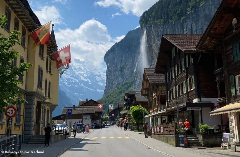 Wooden chalets line the main street of Lauterbrunnen with Staubbach Falls in the distance
