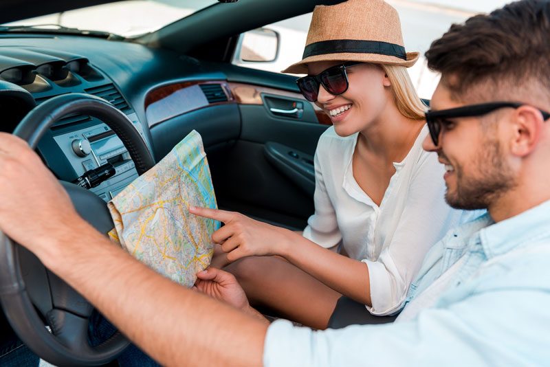 Couple looking at a map whilst seated in a car.